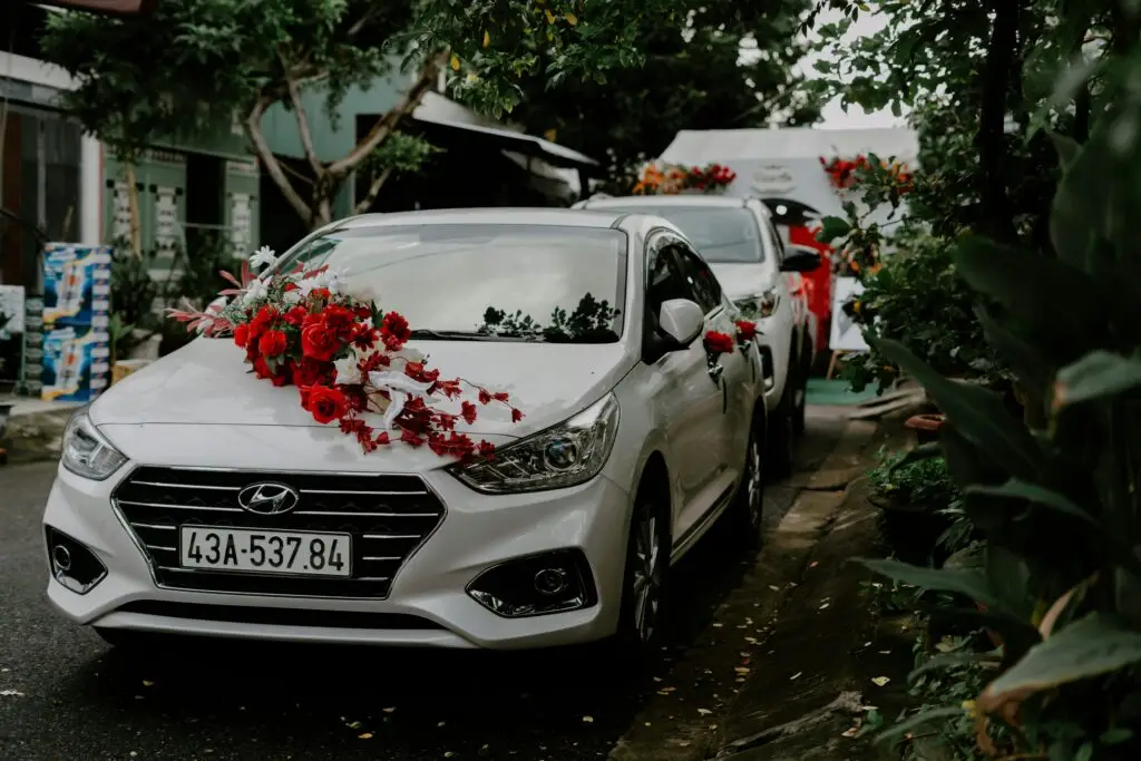 Elegant white car decorated with red roses for a wedding, parked outdoors